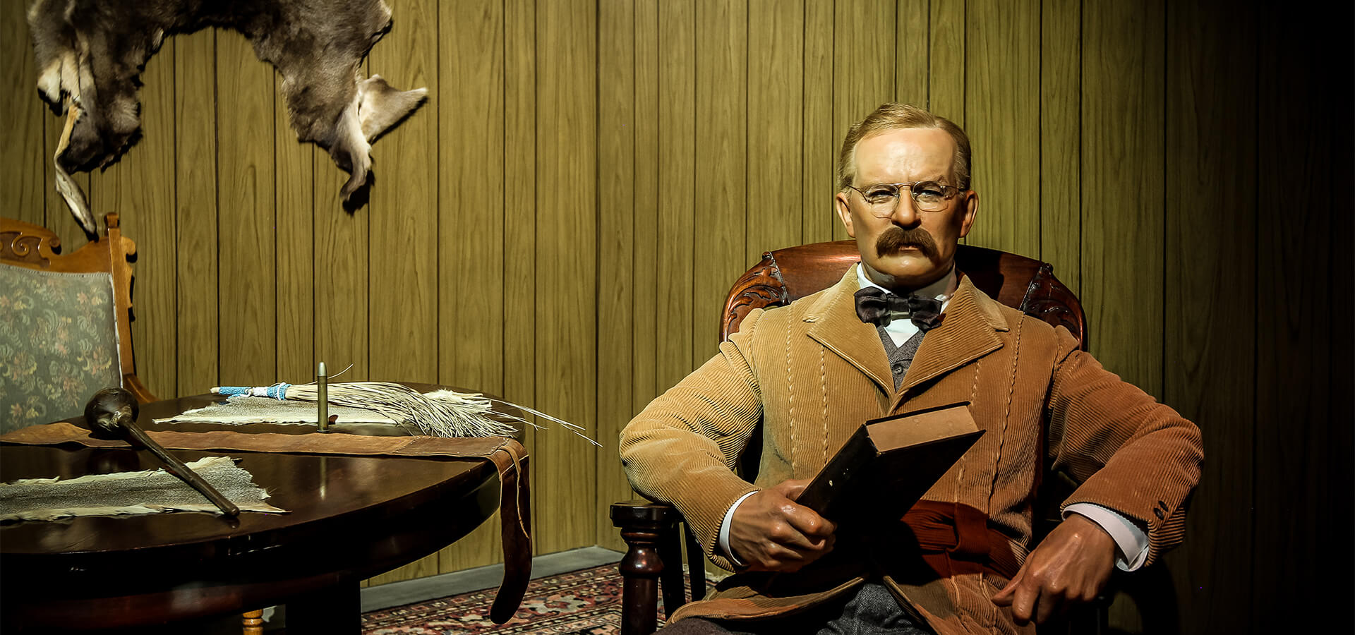 Photo of the Theodore Roosevelt exhibit with Roosevelt sitting in his den.